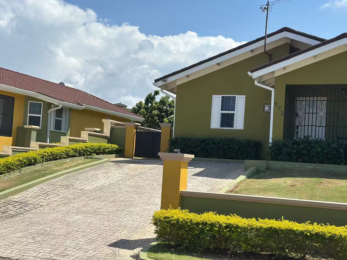 Front of the house with a paved driveway and trimmed hedge