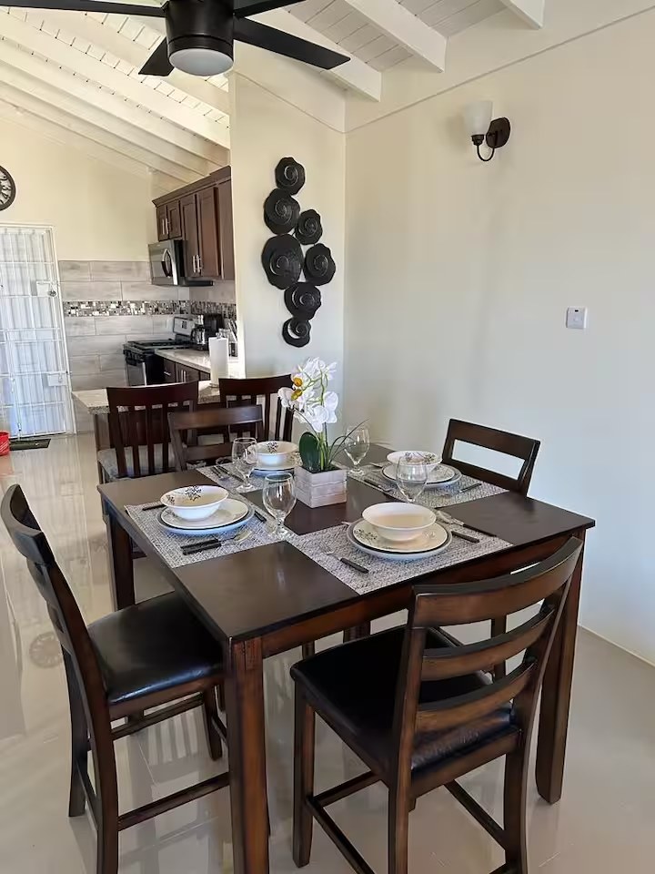 Dining table set for four beside the open kitchen under a beamed ceiling