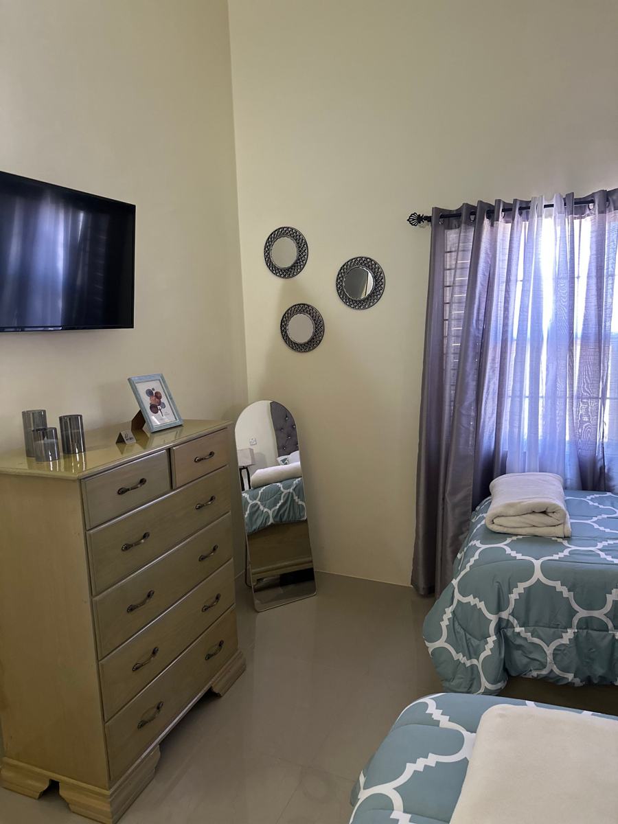 Twin bedroom with a dresser, mirrors and curtains