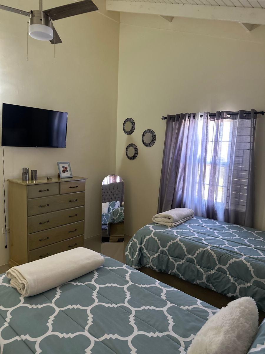 Twin beds with a TV, dresser and ceiling fan