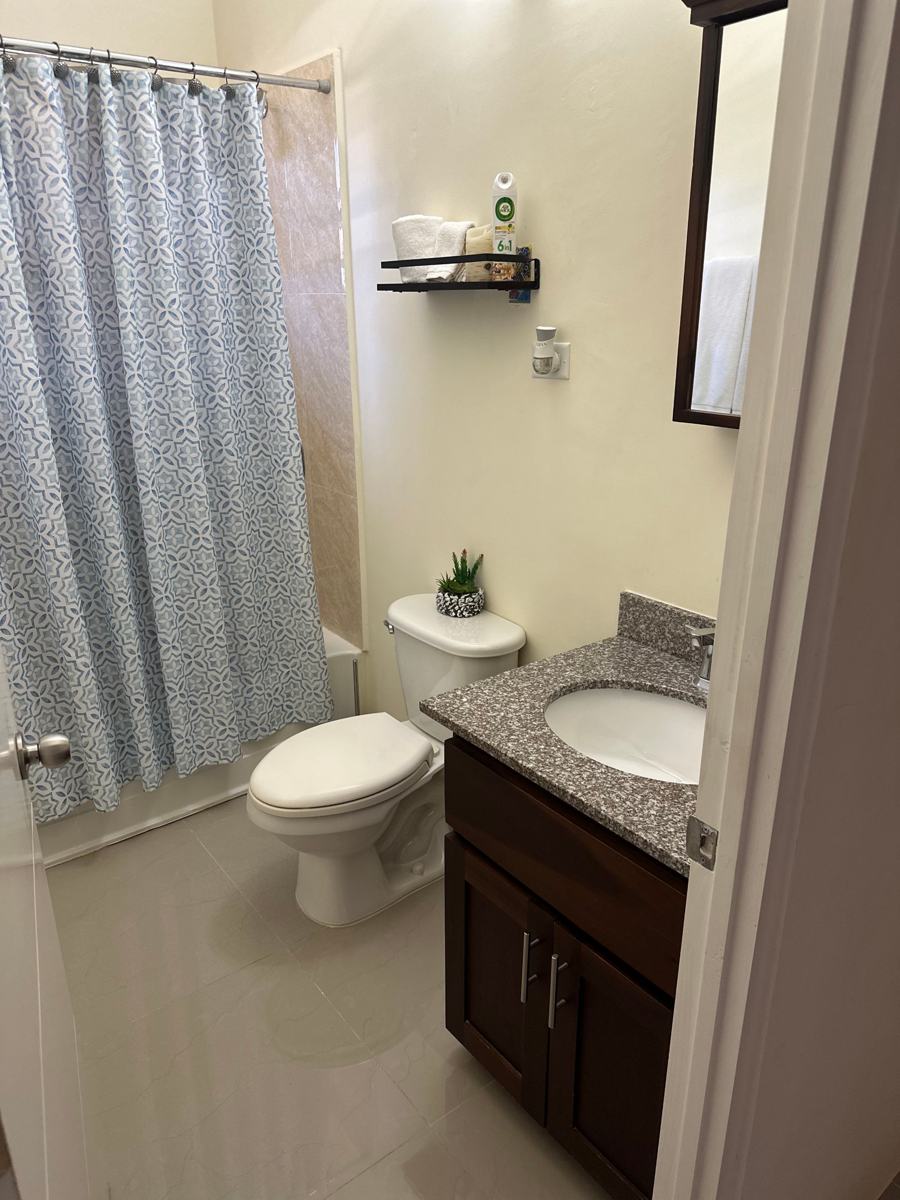 Bathroom with a tub, shower curtain and granite vanity
