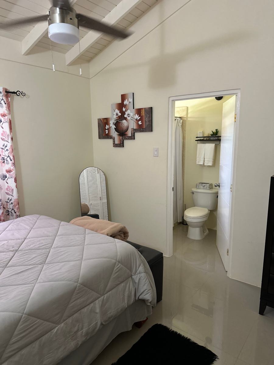 Queen bedroom with a ceiling fan and doorway to the en-suite bathroom