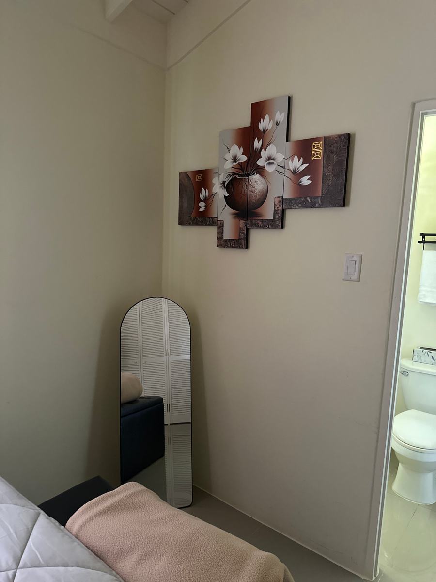 Bedroom corner with wall art, a standing mirror and a view into the bathroom